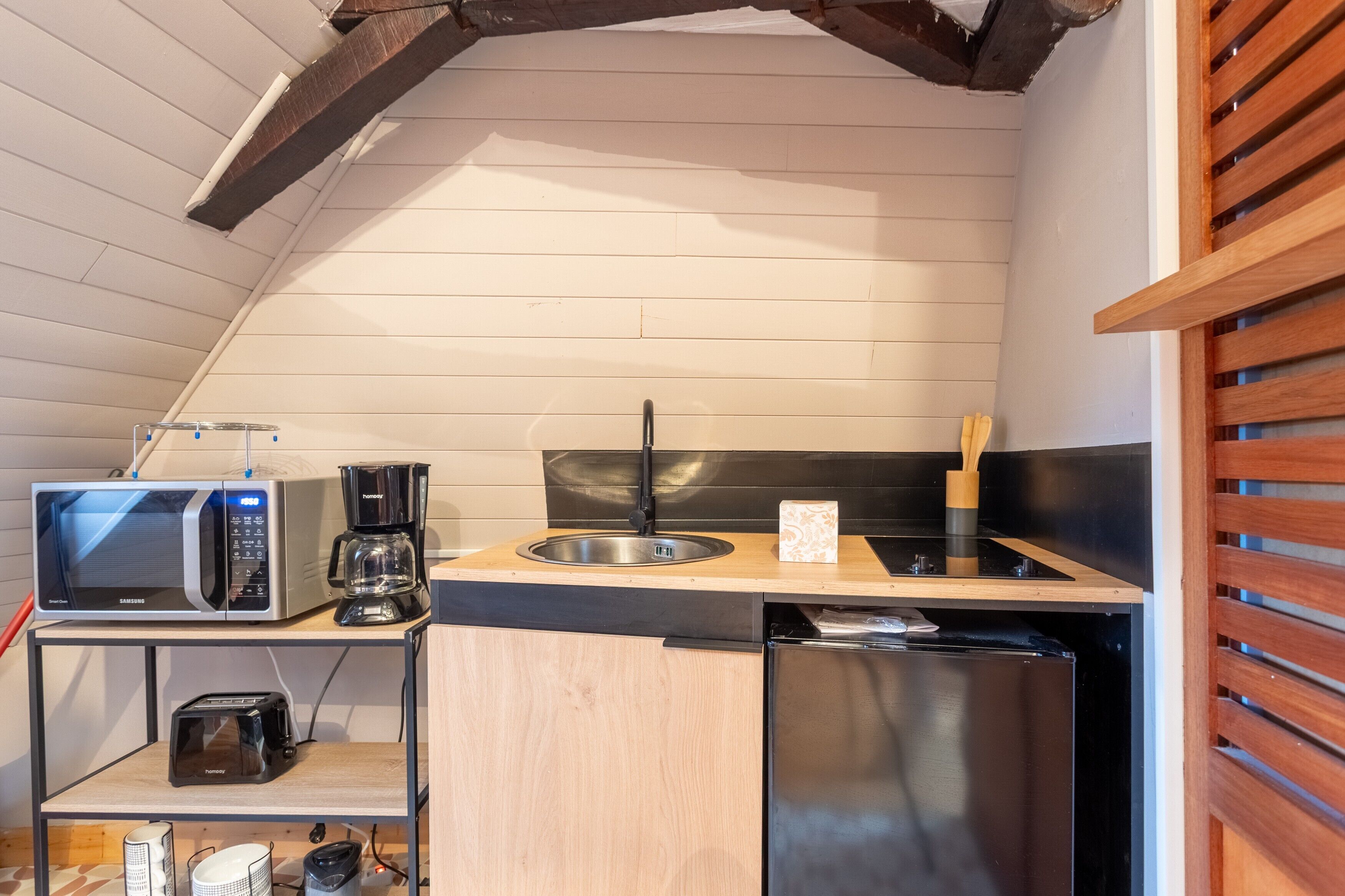 Una cucina compatta con forno a microonde, tostapane, macchina del caffè, lavello e lavastoviglie.