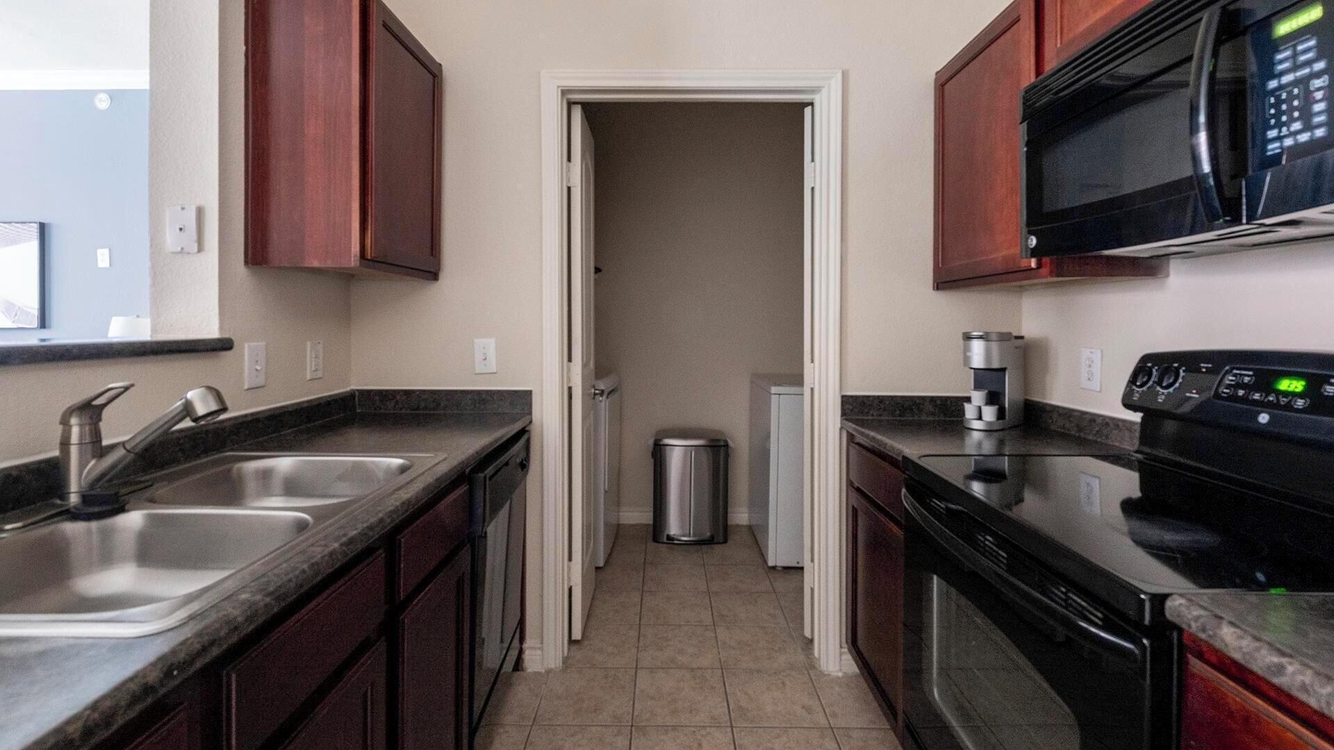 A kitchen with dark wooden cabinets, stainless steel appliances, and a tiled backsplash.