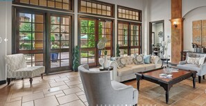 A spacious living room with a large sectional sofa, two armchairs, and a coffee table. The room features large windows with a view of the outside. - Landing | Amazing 1BD, Clubhouse, Gym (Houston)