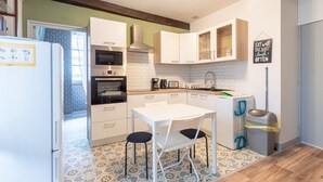 A compact kitchen with white cabinets, a stainless steel refrigerator, a microwave, and a coffee maker. - Apartment 'T2 Alicia' with Wi-Fi (Salies-de-Béarn)