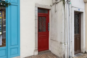 Une porte rouge ornée d’un panneau de verre décoratif, une porte bleue à gauche et un mur blanc sur lequel est affiché le chiffre « 3 ».