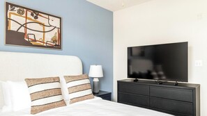 Ein Hotelzimmer mit Bett, Fernseher, Lampe und einem Bild an der Wand.