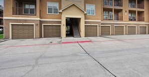 A multi-story building with a central entrance, a staircase, and multiple garage doors. - Landing | Spectacular 2BD, Gym, Clubhouse (Houston)