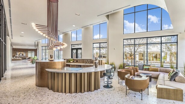 Eine geräumige Lobby mit einer zentralen Rezeption, einer Sitzecke und großen Fenstern mit Blick ins Freie.