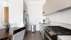 Eine kleine Küche mit einem Edelstahlherd, einer Spüle und einem Kühlschrank.