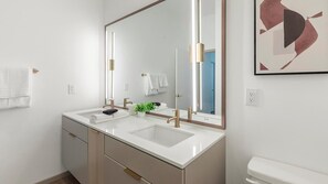 Ein modernes Badezimmer mit zwei Waschbecken, einem großen Spiegel und einer Toilette.