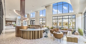 Eine geräumige Lobby mit einer zentralen Rezeption, einer Sitzecke und großen Fenstern mit Blick ins Freie.