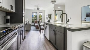 Eine moderne Küche mit Edelstahlgeräten, einer zentralen Kochinsel und einem Essbereich mit Blick ins Freie.