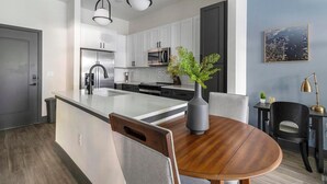 A modern kitchen with white cabinets, stainless steel appliances, and a central island. - Landing | Incredible 1BD, Rooftop Lounge (Jacksonville)