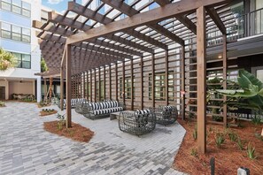 A covered outdoor seating area with wooden beams and planters. - Landing | Stylish 1BD, Gym, Pool (Jacksonville)
