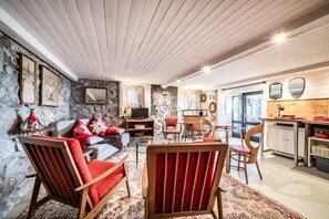 A cozy living room with a stone wall, wooden ceiling, and a dining area with chairs and a table. - Holiday Home “Le Carnotzet Du Lac - Hauts d’Évian” with Lake View, Terrace & Wi-Fi (Larringes)