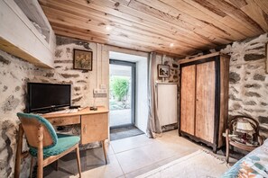 A room with a wooden desk, a chair, a television, a wardrobe, and a view through a glass door. - Holiday Home “Le Carnotzet Du Lac - Hauts d’Évian” with Lake View, Terrace & Wi-Fi (Larringes)