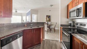 A modern kitchen with granite countertops, stainless steel appliances, and wooden cabinets. - Landing | Beautiful 2BD, Clubhouse, Gym (Lewisville)