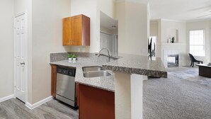 Eine moderne Küche mit Granitarbeitsplatten, Edelstahlgeräten und Holzschränken.