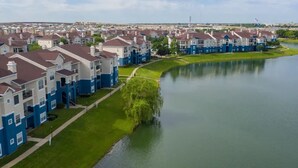 A residential area with modern two-story houses, a small lake, and a clear sky. - Landing | Stylish 2BD, Clubhouse, Gym (Lewisville)