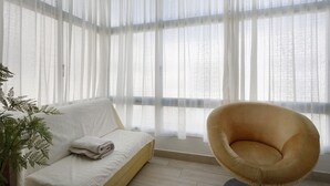 Ein Zimmer mit einem Bett, einem Sessel und durchsichtigen Vorhängen.