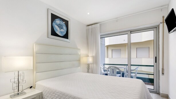 Ein Schlafzimmer mit einem Bett, einem Nachttisch, einer Lampe und einem Bild an der Wand.