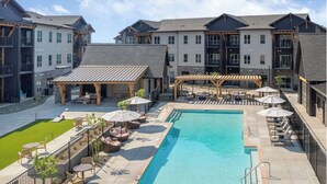 A modern hotel with a central pool, outdoor seating, and a covered patio area. - Landing | Spectacular 1BD, Pool, Game Room (Prescott Valley)