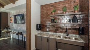 A modern kitchen with a brick backsplash, marble countertop, and built-in cabinets. - Landing | Spectacular 1BD, Pool, Game Room (Prescott Valley)