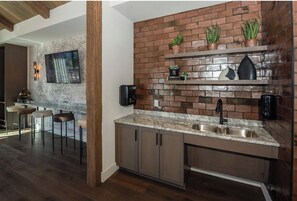 A modern kitchen with a brick backsplash, marble countertop, and built-in cabinets.