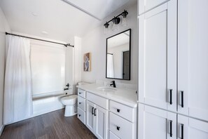 Ein modernes Badezimmer mit Badewanne, Toilette und Waschtisch mit Schränken.