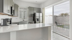 A modern kitchen with a large island, stainless steel appliances, and a sliding glass door leading to a patio. - Landing | Stunning 1BD, Gym (Phoenix)