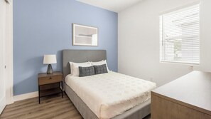 A bedroom with a bed, bedside table, lamp, and a window with blinds. - Landing | Modern 1BD, Gym (Phoenix)