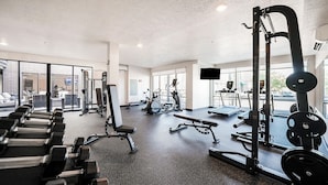 Ein Fitnessstudio mit verschiedenen Trainingsgeräten, großen Fenstern und Blick auf die Straße.