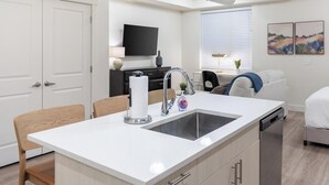 Une cuisine moderne dotée d’un îlot central, d’un lave-vaisselle encastré et d’un téléviseur à écran plat fixé au mur.