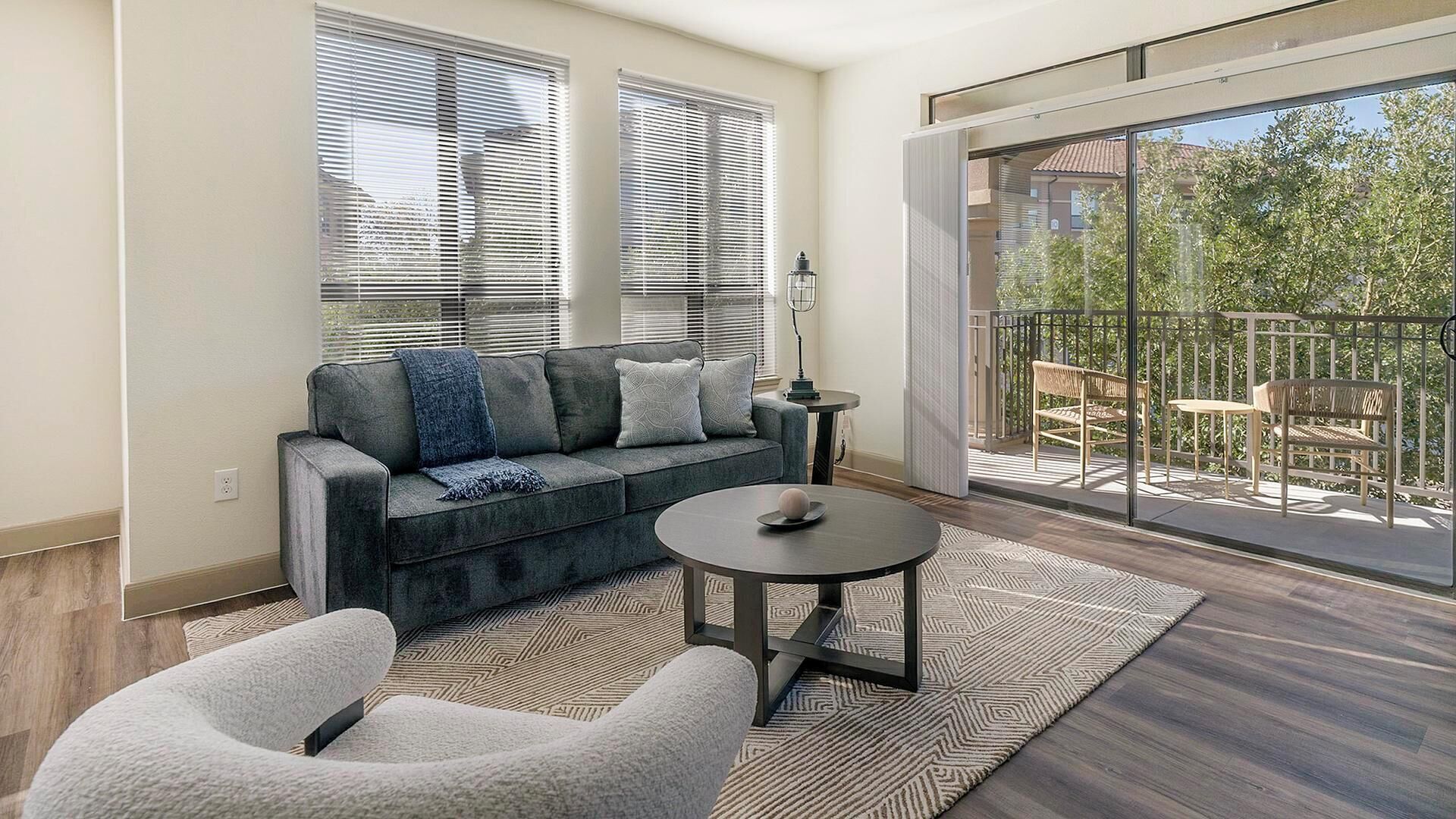 A modern living room with a grey sofa, a round coffee table, and a patterned rug.