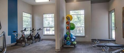A gym with stationary bikes, exercise balls, and benches.
