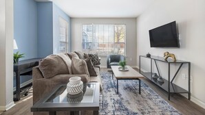 A modern living room with a sofa, coffee table, and TV. - Landing | Modern 1BD, Clubhouse, Gym (Murfreesboro)