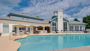 A poolside area with a pool, lounge chairs, and a building with a blue and white color scheme. - Landing | Modern 1BD, Clubhouse, Gym (Murfreesboro)