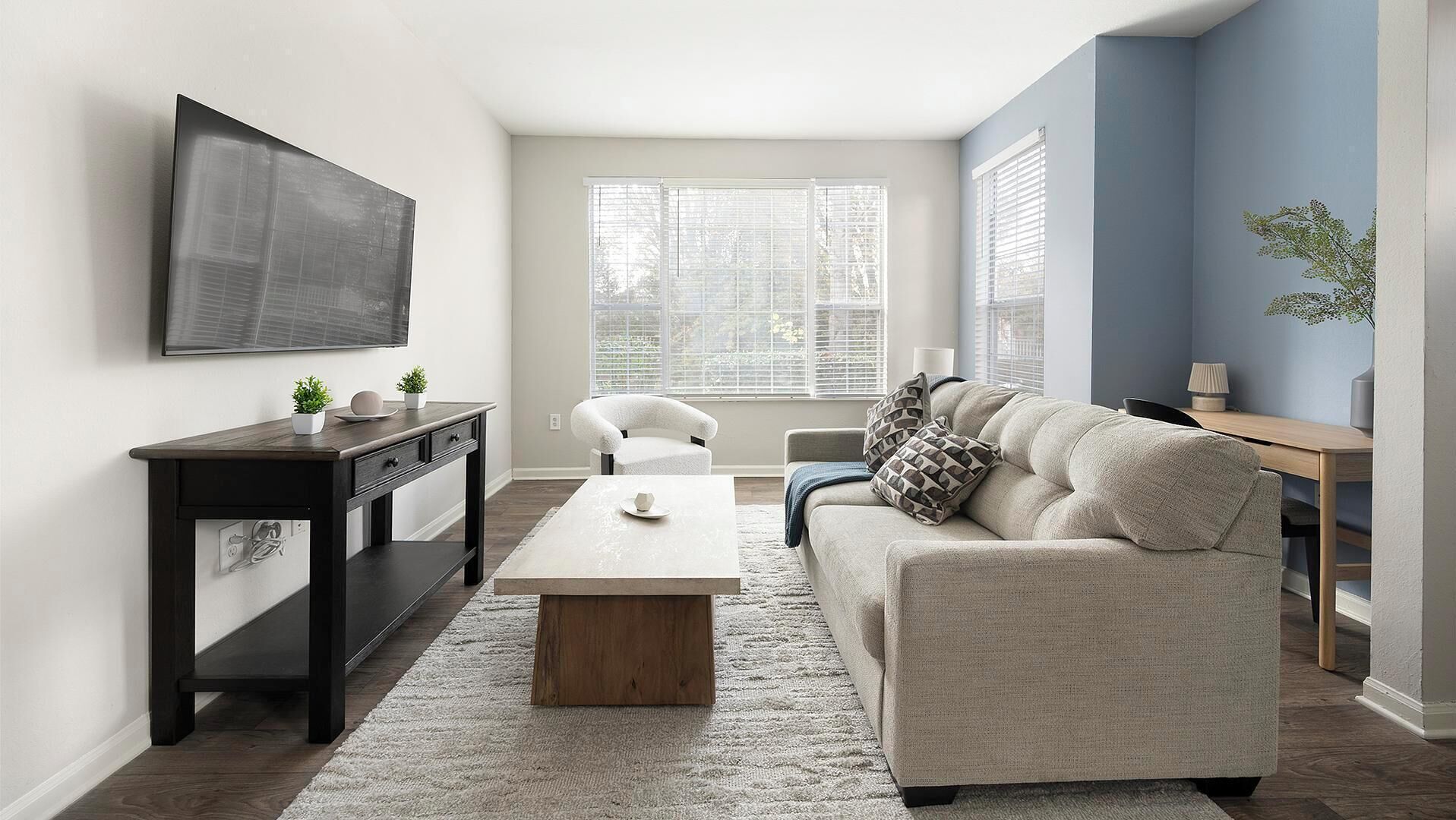 A modern living room with a sofa, coffee table, and a TV mounted on the wall.