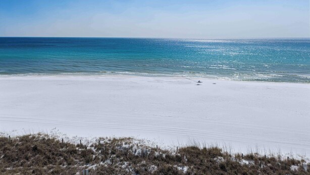 Ein Strand mit weißem Sand und klarem, blauem Wasser.