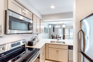 A modern kitchen with stainless steel appliances, a dishwasher, and a large window providing natural light. - Exclusive 2BR condo w/ pools & hot tub (Miramar Beach)