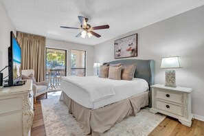 A bedroom with a bed, a ceiling fan, a TV, a desk, and a chair. - Exclusive 2BR condo w/ pools & hot tub (Miramar Beach)