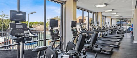 A gym with exercise equipment, large windows, and a view of the outdoors.