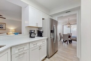 A modern kitchen with white cabinets, a stainless steel refrigerator, and a coffee maker on the counter. - Steps to Beach & Tennis | Resort Luxury (Miramar Beach)
