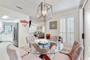A modern kitchen with a glass dining table, a stainless steel refrigerator, and a decorative sign. - Steps to Beach & Tennis | Resort Luxury (Miramar Beach)