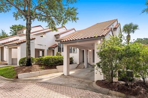 A residential building with a tiled roof, a covered porch, and a paved driveway. - Exclusive Beach Access & Tennis Court Views (Miramar Beach)