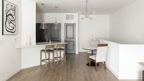 A modern kitchen with a central island, pendant lights, and a dining area with a round table and chairs. - Landing | Stunning 1BD, Clubhouse, Gym (Madison)
