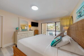 A bedroom with a bed, a dresser, a chair, a television, and a balcony with a view. - Exclusive 2BR tennis condo with beach access (Miramar Beach)