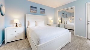 Quarto com uma cama, duas mesas de cabeceira, um criado-mudo, um espelho e um guarda-roupa.