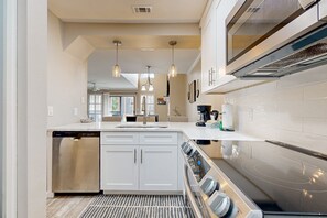 A modern kitchen with a dishwasher, oven, and a large island with a sink. - Coastal retreat with free resort shuttle (Miramar Beach)