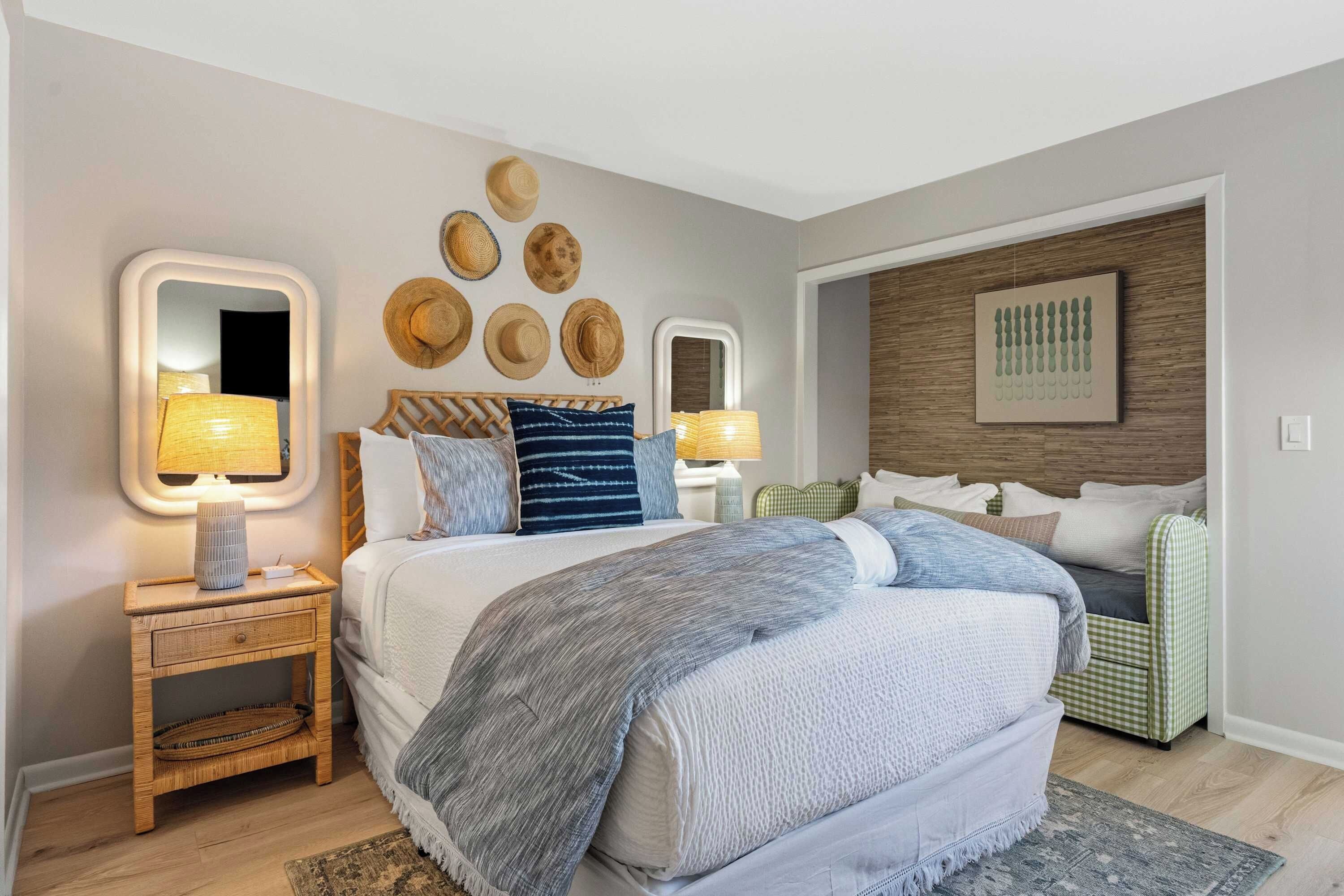 A modern bedroom with a large bed, bedside lamps, a wall-mounted mirror, and a framed picture.