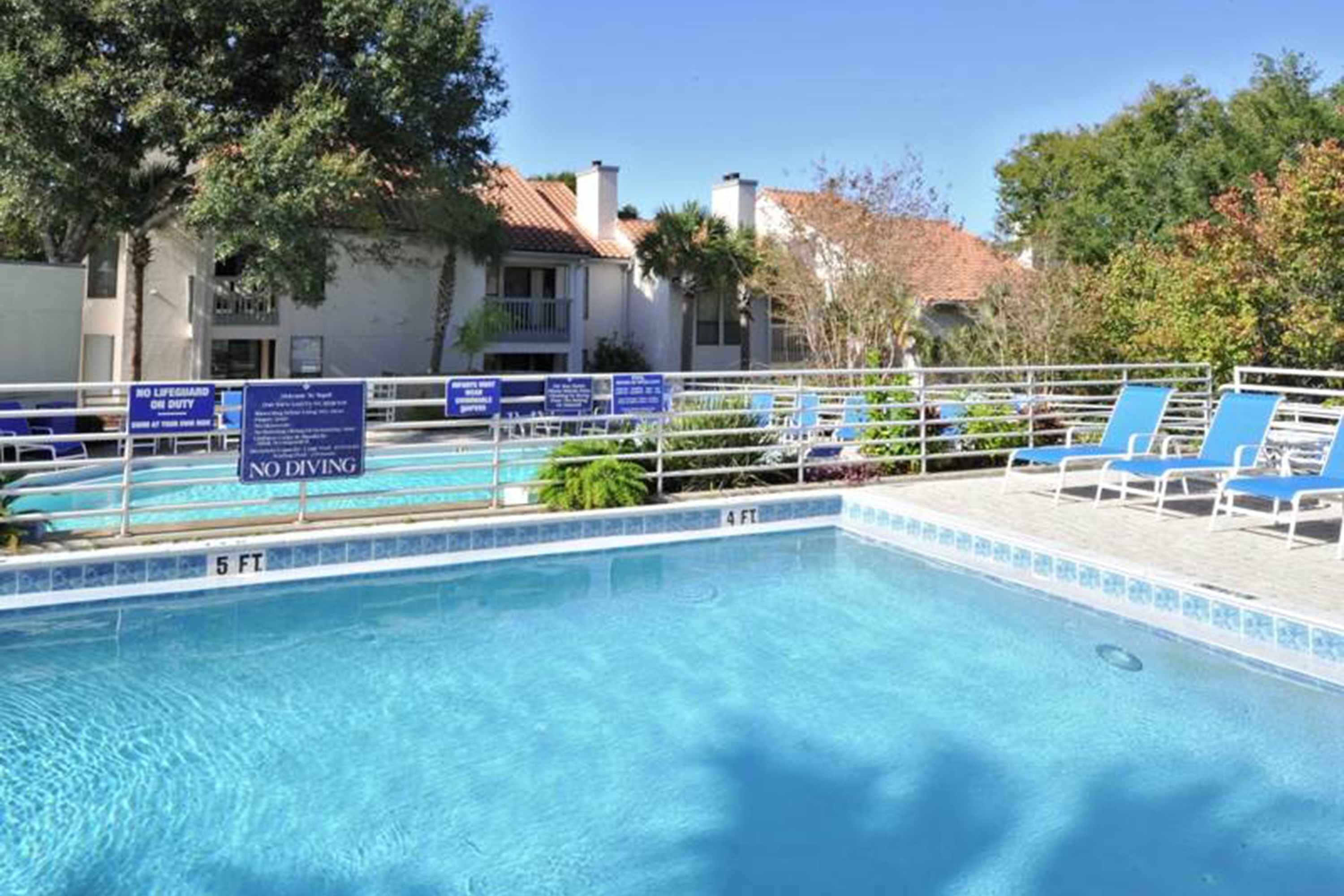 A swimming pool with lounge chairs and a no diving sign.