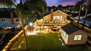 Une maison à deux étages avec un balcon, une pelouse et des guirlandes lumineuses.