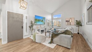 Un salon spacieux doté d’un grand téléviseur à écran plat, d’un canapé confortable, d’une table basse et d’un plancher en bois.