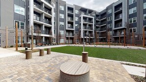 A modern apartment building with multiple balconies and a central courtyard with seating areas. - Landing | Spectacular 1BD, Courtyard, Clubhouse (Decatur)